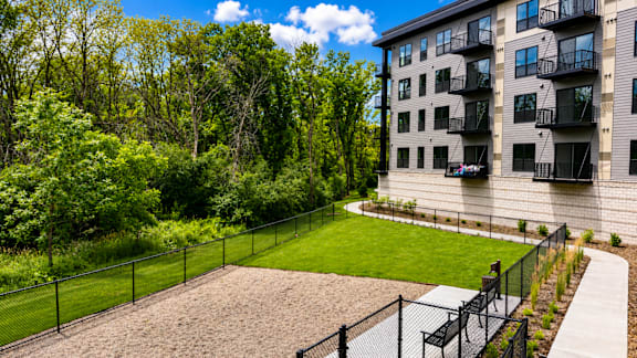A black fence surrounds a sandy area in front of a building.
