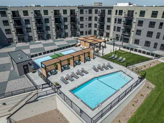 A large outdoor swimming pool surrounded by a black fence and a wooden deck with chairs.