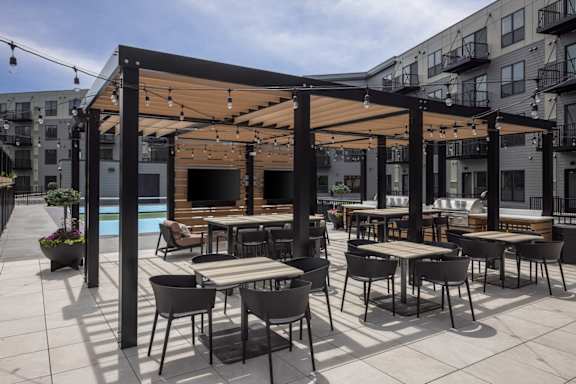 A patio with tables and chairs and a pool in the background.