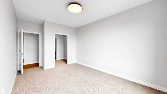 A room with a carpeted floor and two open doors.