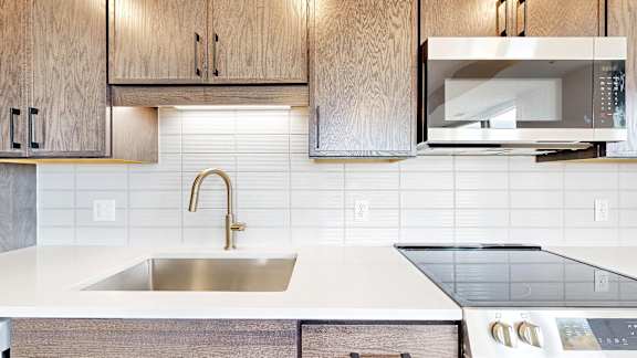 A modern kitchen with a stainless steel sink and wooden cabinets.