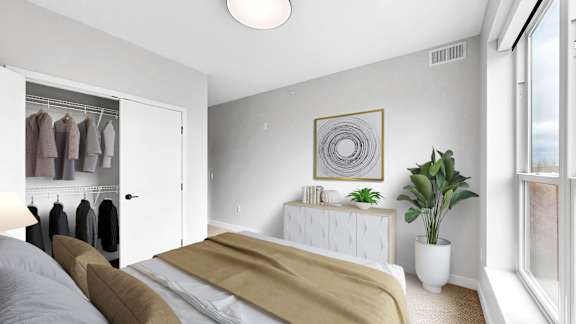 A bedroom with a bed, a plant, and a wardrobe.