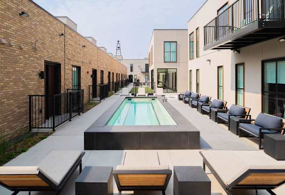 A pool surrounded by black railings and concrete benches.