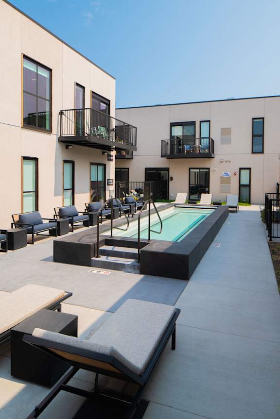 A modern building with a pool and lounge chairs.