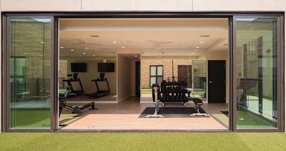 A gym with a green floor and a glass wall.