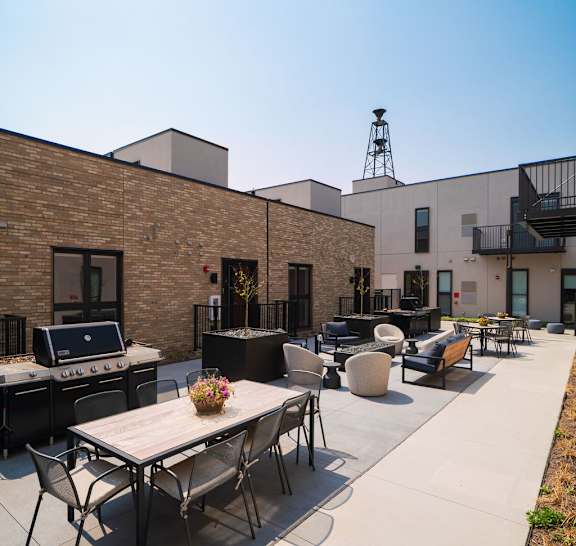 A patio with a table and chairs is surrounded by a brick building.