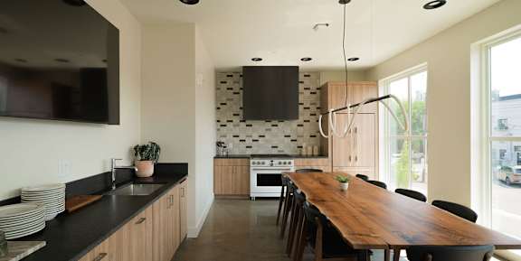 A modern kitchen with a wooden table and black countertops.