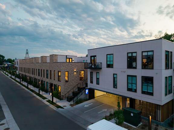 A modern building with a flat roof and a parking lot in front.