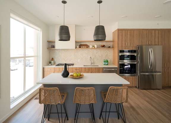 A modern kitchen with a large island and chairs.