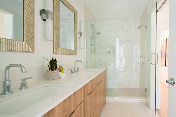 A bathroom with a white counter top and a glass shower.