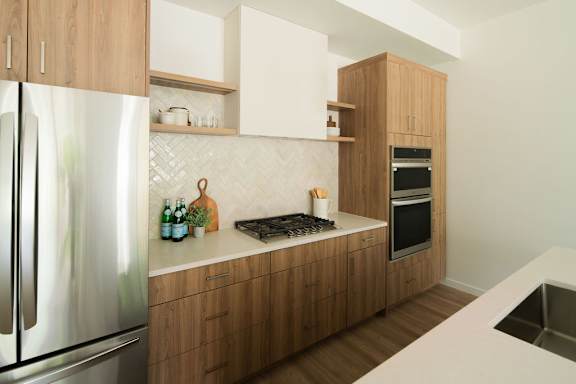 A modern kitchen with wooden cabinets and a stainless steel refrigerator.