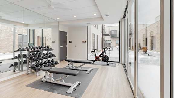 A gym with a variety of equipment including weights and a rowing machine.