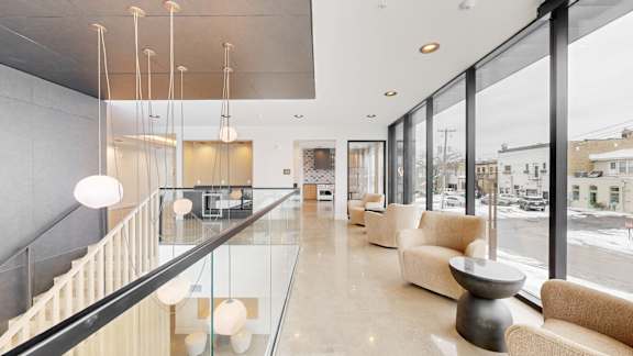A modern living room with a glass railing and a glass table.