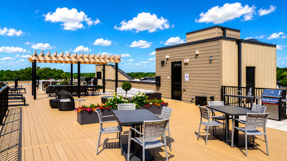 A wooden deck with a table and chairs and a building in the background.