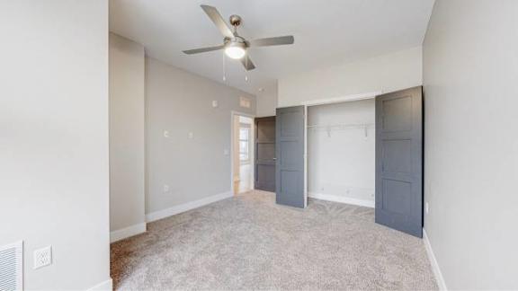 A room with a ceiling fan and carpeted floor.