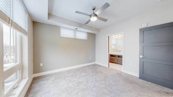 A room with a ceiling fan and a window with blinds.