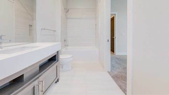 A white bathroom with a sink, toilet, and a mirror.