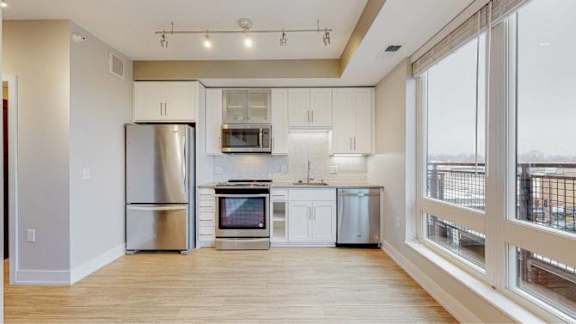 A kitchen with stainless steel appliances and wooden floors.