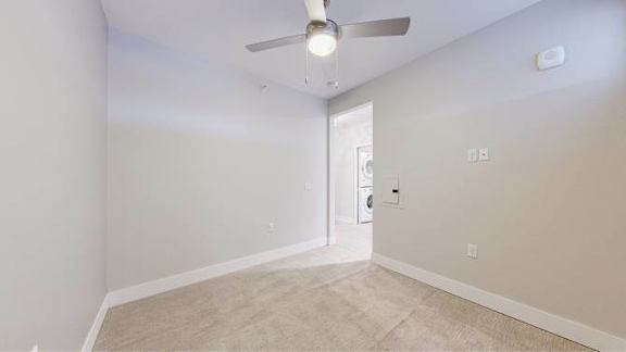 A room with a ceiling fan and carpeted floor.
