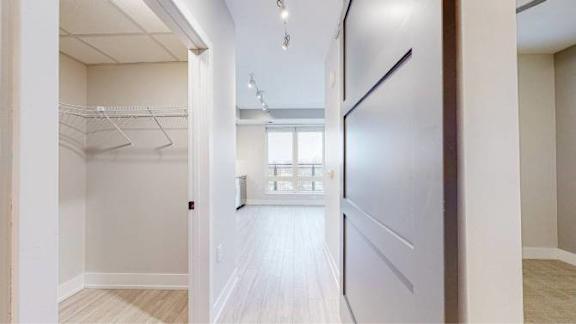 A white hallway with a wooden floor and a white door on the right.