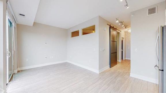 A spacious room with white walls and wooden flooring.