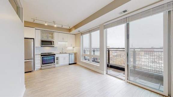 A spacious kitchen with a refrigerator, microwave, oven, and a dining table with chairs.