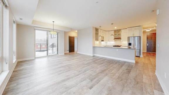 A spacious living room with a kitchen in the background.