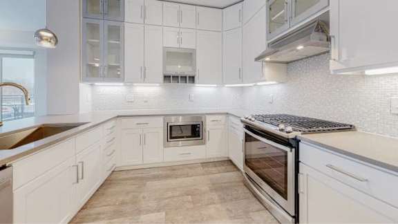 A modern kitchen with white cabinets and a tiled backsplash.