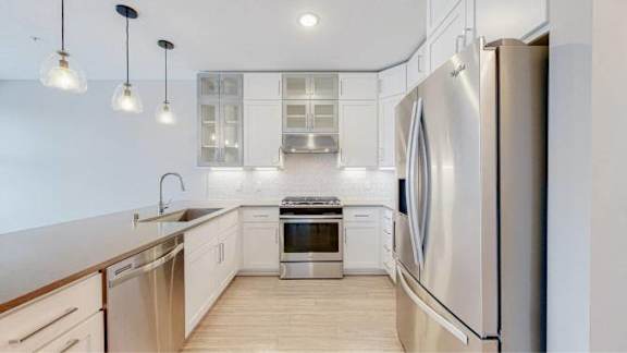 A modern kitchen with stainless steel appliances and wooden flooring.