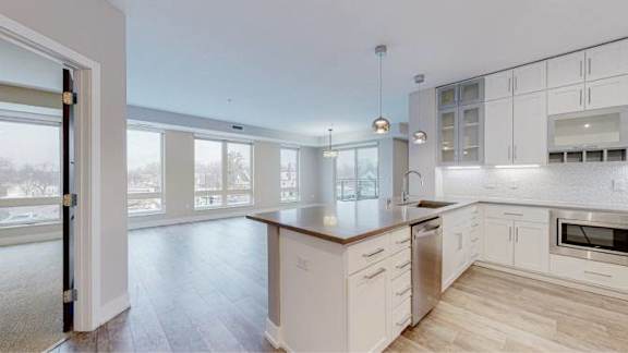 A kitchen with white cabinets and a wooden island.