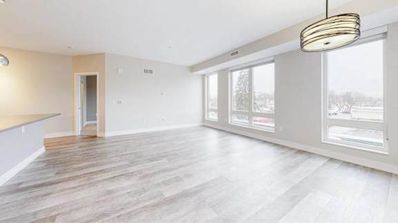 A spacious room with wooden flooring and a large window.
