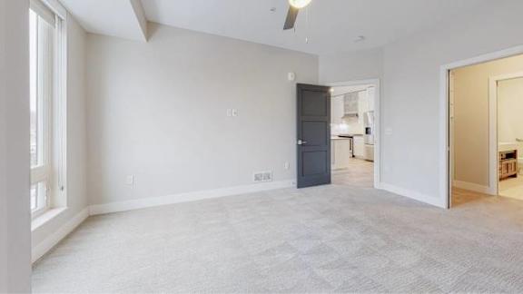 A spacious room with a ceiling fan and a door leading to another room.