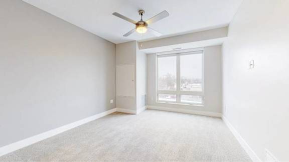 A room with a ceiling fan and a sliding glass door.