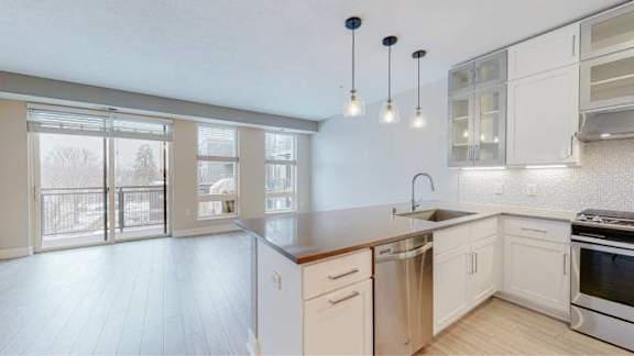 A kitchen with white cabinets and a wooden floor.