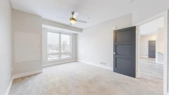 A room with a ceiling fan and a large window.