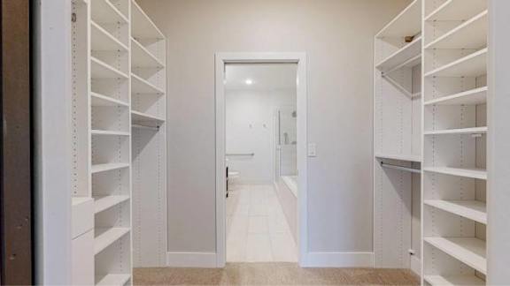 A hallway with white shelves on both sides leading to a white door.