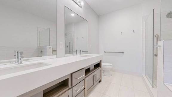 A white bathroom with a sink, mirror, and toilet.