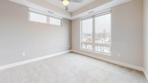 A room with a large window and a ceiling fan.