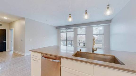 A kitchen with a sink and cabinets under a window.