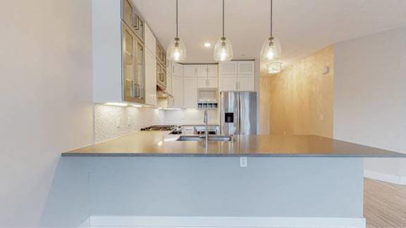 A modern kitchen with a stainless steel countertop and pendant lights.
