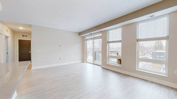 A spacious room with wooden flooring and large windows.