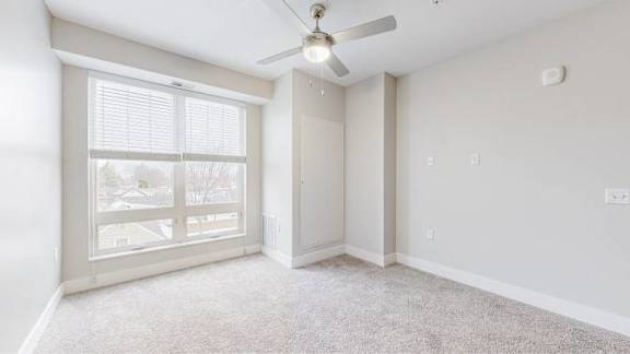 A room with a ceiling fan and carpeted floor.