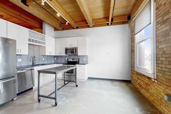 A kitchen with a brick wall and a window.