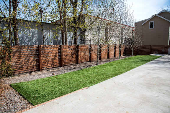 A long wooden fence runs along a grassy area.