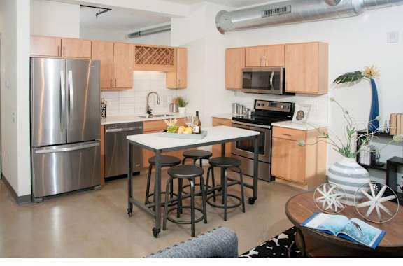 A kitchen with a refrigerator, microwave, oven, and sink.