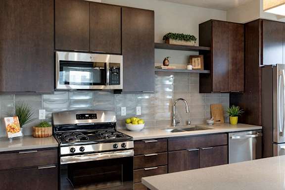 A modern kitchen with dark wood cabinets and stainless steel appliances.
