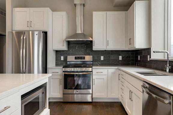 A modern kitchen with white cabinets and stainless steel appliances.