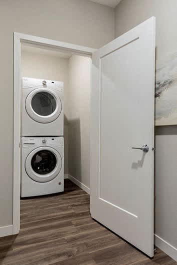 A white door opens to a laundry room with a washer and dryer.