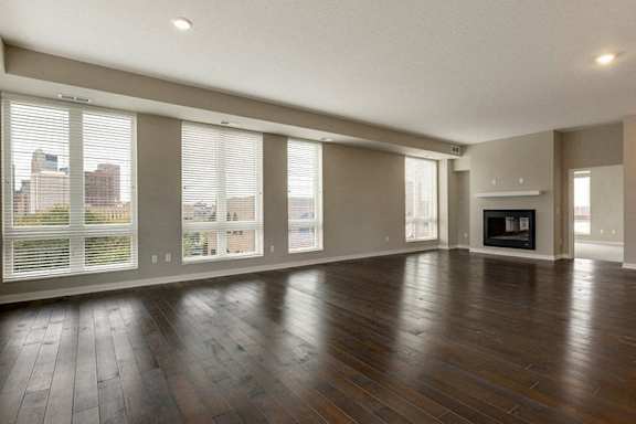 A large empty room with wooden floors and a fireplace.