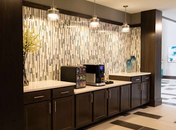 A modern kitchen with dark wood cabinets and a white countertop.at The Edison at Avonlea, Lakeville, 55044